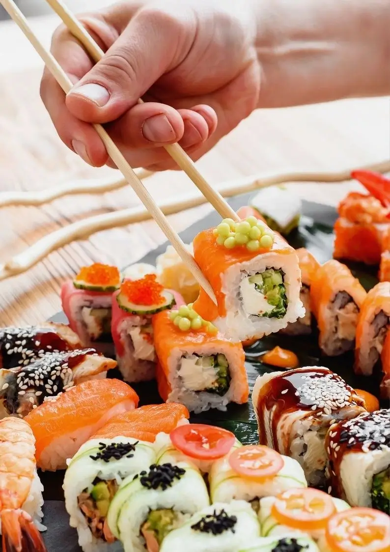 Hand holding sushi using chopsticks